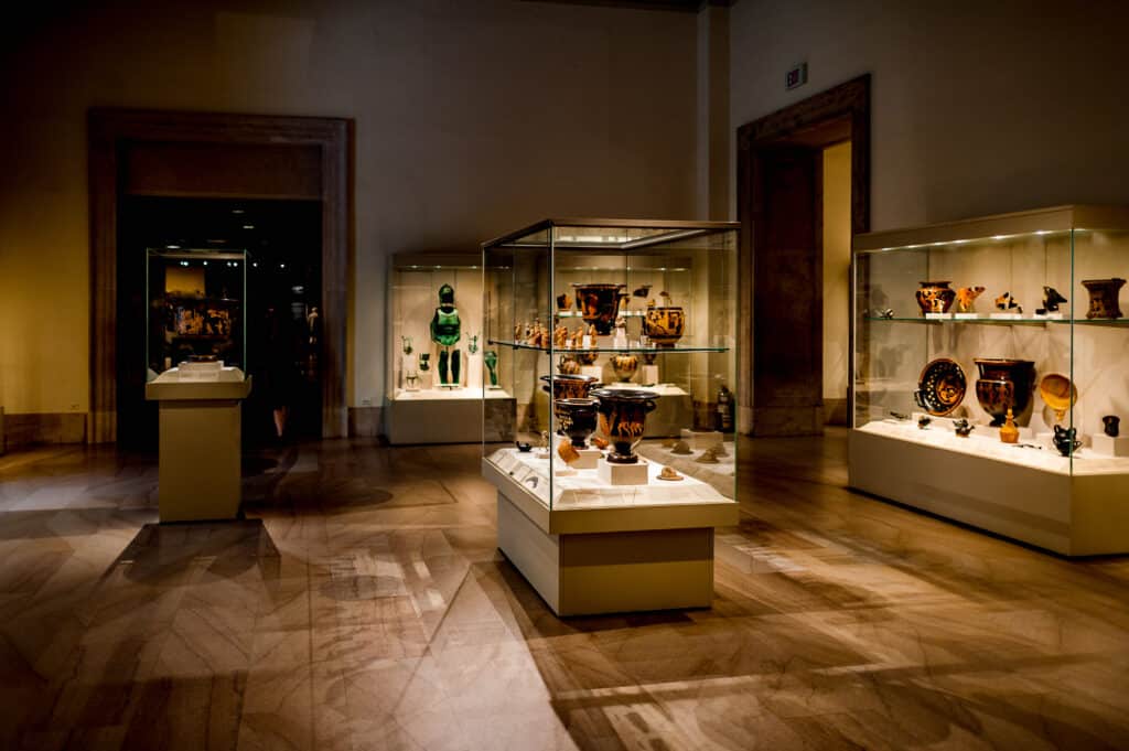 Museumssaal mit antiken Keramikgefäßen und archäologischen Sammlungsstücken in beleuchteten Glasvitrinen