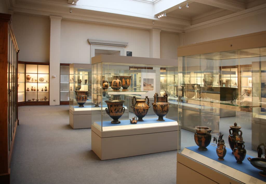 Museumsausstellung mit antiken Keramikgefäßen und historischen Artefakten in modernen Vitrinen.
