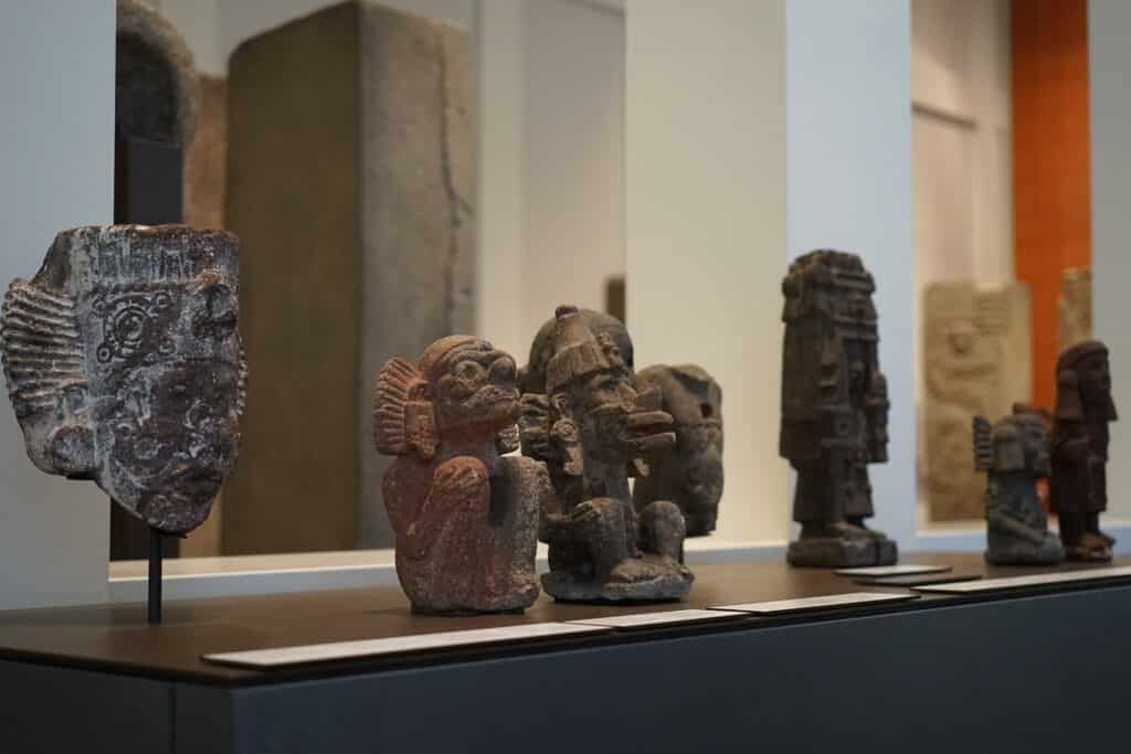 Präkolumbianische Figuren und historische Skulpturen in einer musealen Ausstellung.