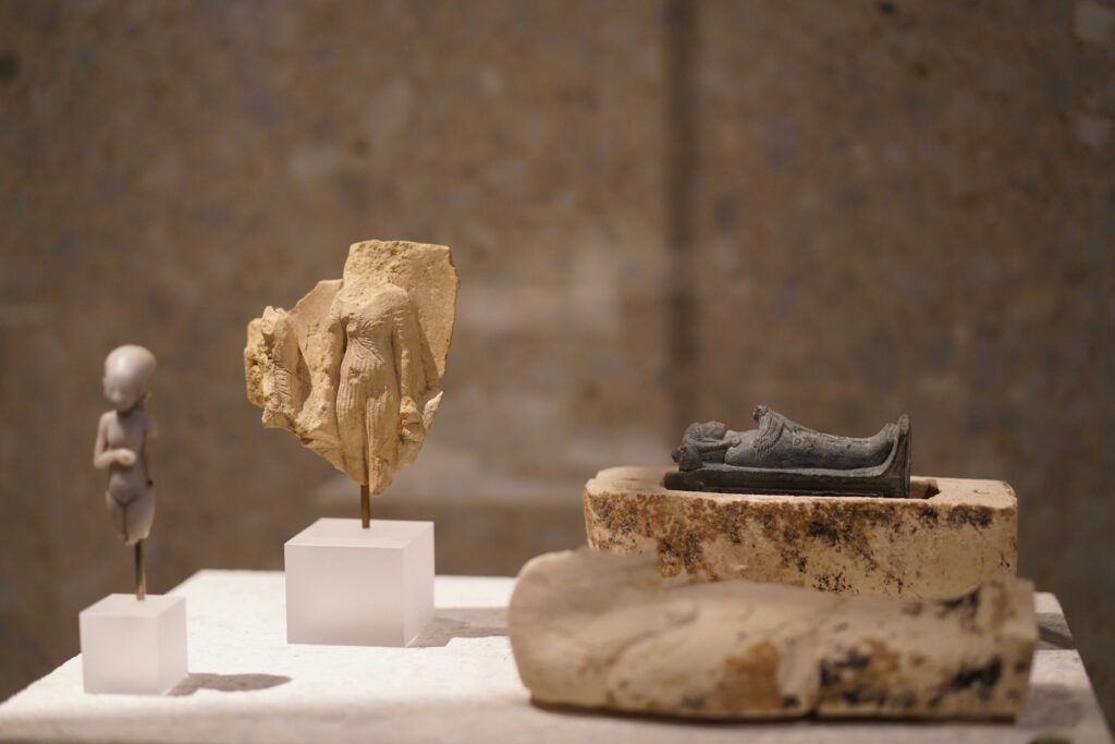 Kleine antike Figuren und archäologische Artefakte in einer musealen Ausstellung präsentiert.